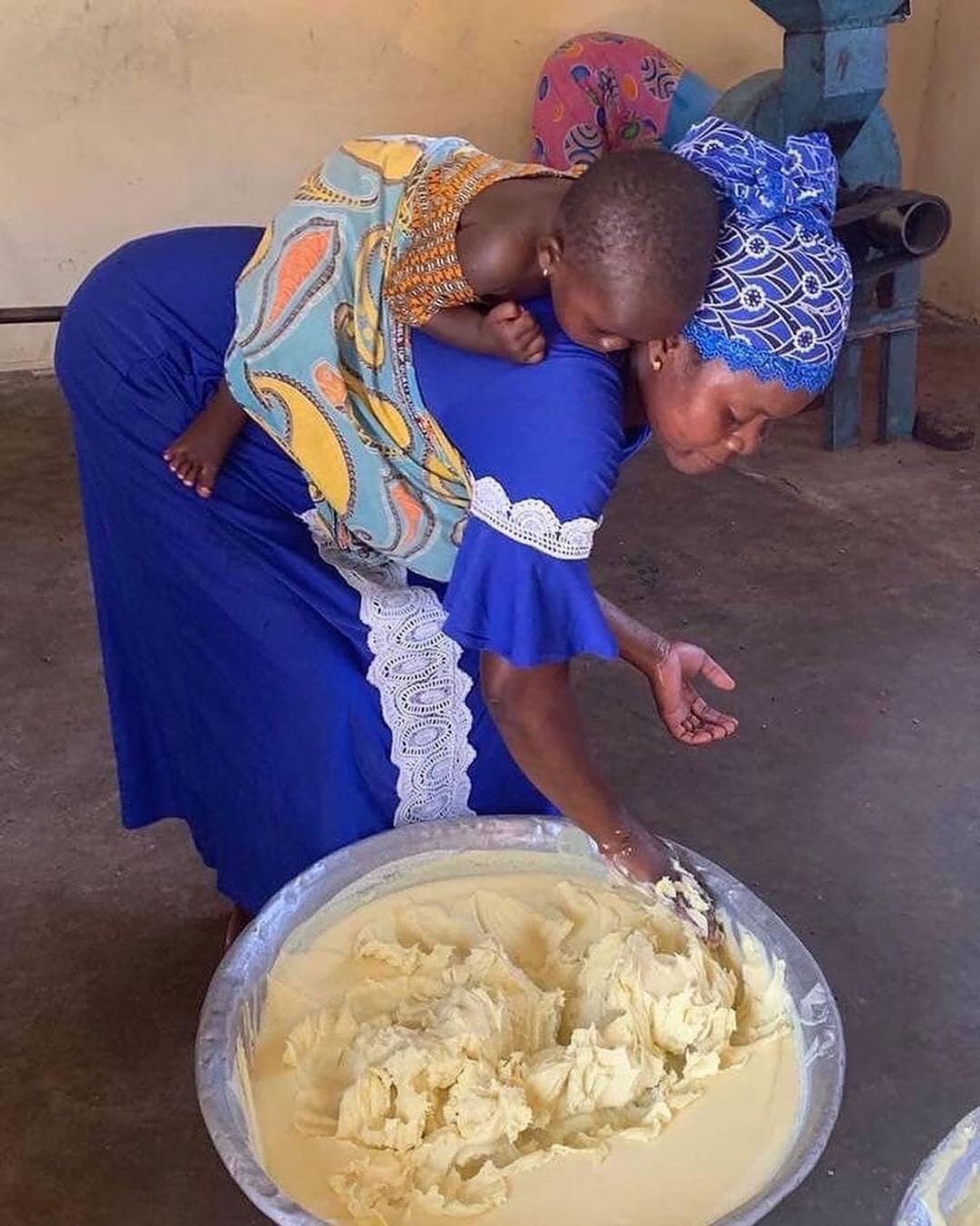 woman making shea with her child on her back