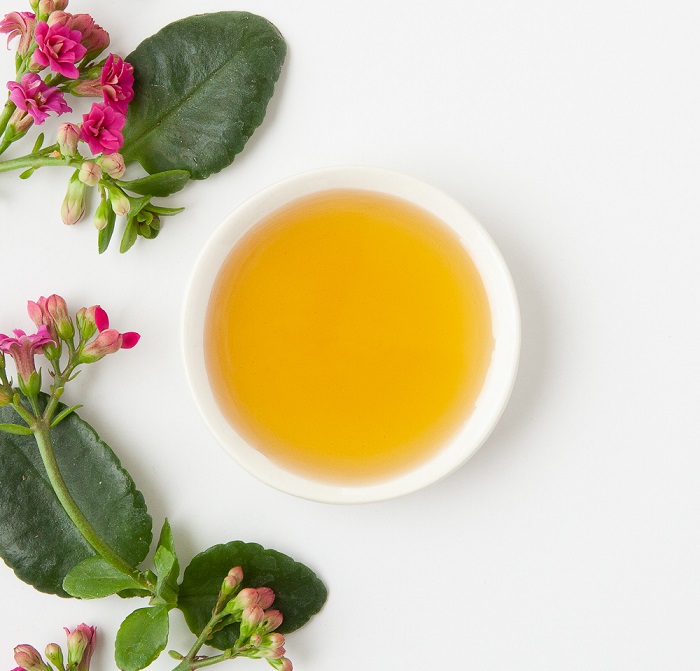 A bowl of yellowish bakuchiol surrounded by flowers